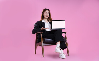 full body image of asian businesswoman using laptop on pink background