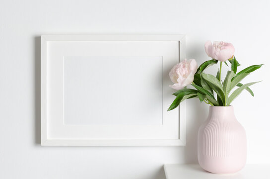 Landscape picture frame mockup on white wall with peony flowers, blank mockup with copy space