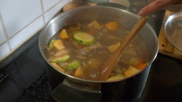 View of a vegetable soup being stirred in a steaming pot in slow motion 4K