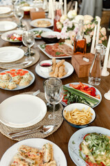 decoration of the wedding banquet. Rustic wooden decor. Festive table with desserts, appetizers, cakes, salads and french fries. Banquet table at the wedding.