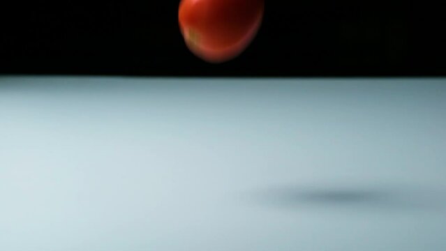 Slow Motion Shot of Tomatoes of Different Colours Falling, Bouncing and Rolling onto a White Surface untill they Stop Moving (HD)