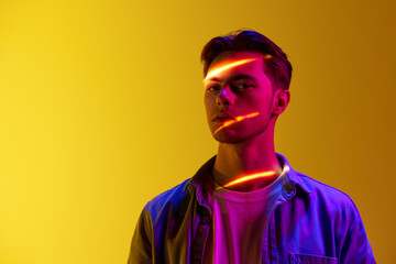 Handsome young man in casual stylish clothes with digital neon filter reflection on face standing...