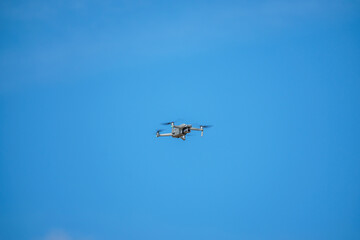 Fototapeta na wymiar a drone with a high-resolution digital camera flies against a blue sky with clouds, a drone hovers in the air against the sky, a copter hovers in the air