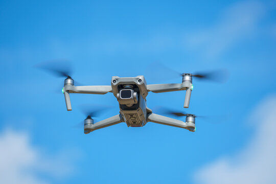 a drone with a high-resolution digital camera flies against a blue sky with clouds, a drone hovers in the air against the sky, a copter hovers in the air