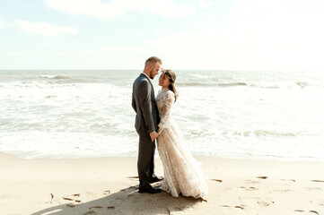 happy wedding couple having fun being on the wild ocean beach. the bride and groom run along the beach and laugh. newlyweds at sea