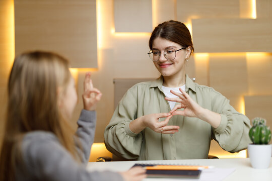 A woman teacher communicates with a deaf child at school.