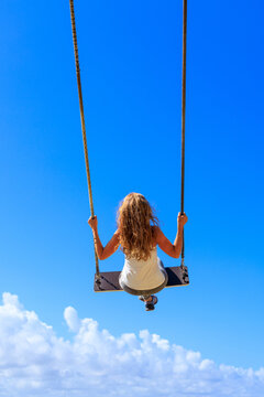 woman on swing on blue sky
