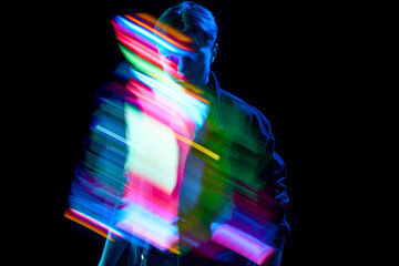 Surreal, virtual reality. Young man with mixed, multi colored, digital neon stripes reflection over...