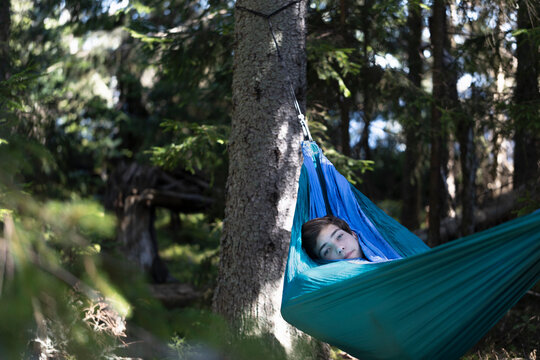 Boy relaxing in hammock in forest