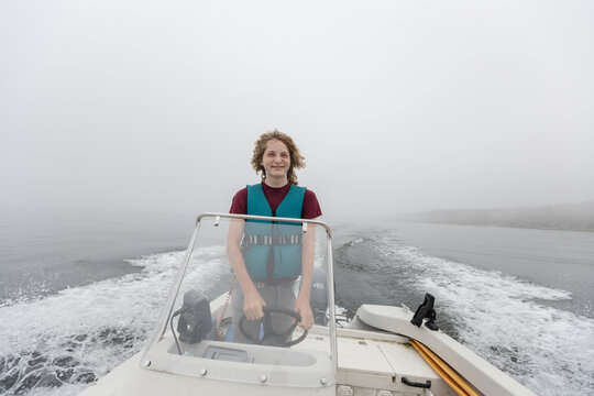 Boy steering motorboat on foggy lake