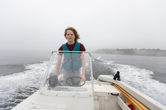 Boy steering motorboat on foggy lake