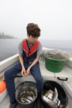 Boy sitting in boat on foggy lake