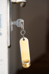 clef dans la serrure d'une porte avec un gros porte clef d'hôtel 