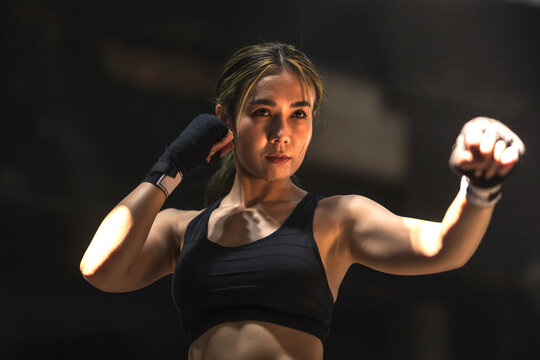 Portrait young confident female sport Muay Thai Boxing training, muay Thai boxer woman concentrate and ready to fight, Thai boxing concept
