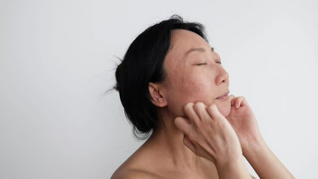 Young asian woman doing face building facial gymnastics self massage and rejuvenating exercises touching chin