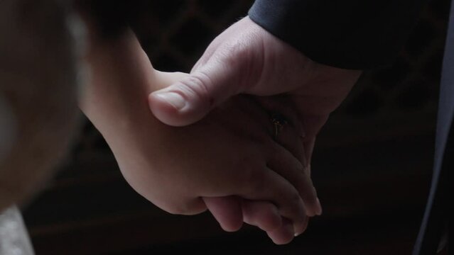 Newlywed wedding couple holding hands together in union close up