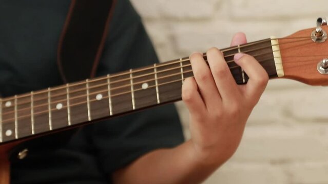 Close up of young man's hand playing classical guitar practicing to master the guitar chord skillfully and fluently.