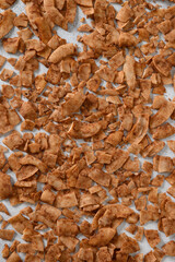 Pattern of Coconut chips with cinnamon. Vegan and sugar free dessert. Vertical format. Sri lankan local food. Home drying.