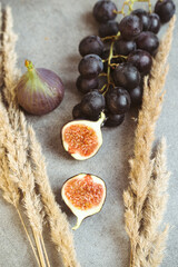 Autumn attributes. Croissant, dark grapes, book and figs on the grey table. Gold October