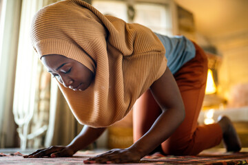 Young muslim black woman praying at home