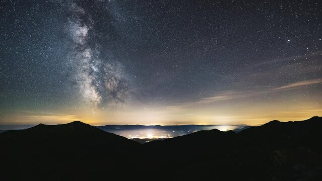 Starry night sky with Milky Way Galaxy in mountains landscape Astronomy Time lapse, Stars motion over Countryside traffic Night to day