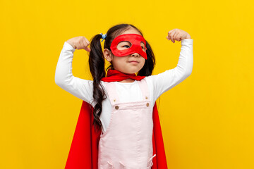 little asian girl in superman costume and mask showing biceps and power gesture, korean kid in superhero cape