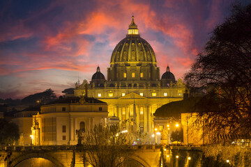 Romantic photo of St. Peter's basilica in the Vatican at sunset with red and fiery clouds. Church...
