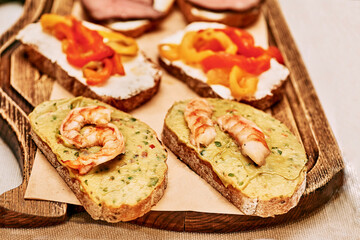 Delicious sandwiches with vegetable sauce and boiled shrimps on a wooden tray