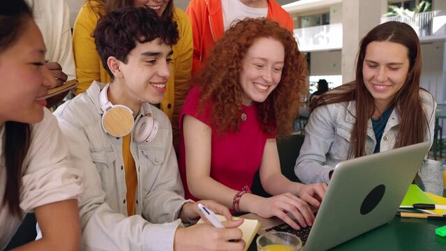 Young group of student people studying together at college campus. High school millennial teenage classmate working on laptop sitting at cafeteria table. Education concept.