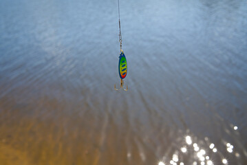 Bait in the form of a colored spinner on the background of the water surface. Fishing on spinning....