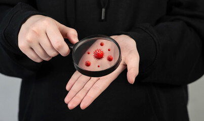 A man shows dirty hands through a magnifying glass with viruses, bacteria and microbes. Hygiene...