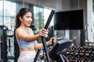 Fototapeta na wymiar Young asian girl jogging on a treadmill in a gym, Muscular athletes actively training in the gym, Female training at fitness center. Woman exercising cardio workout, exercise lose weight, listen music