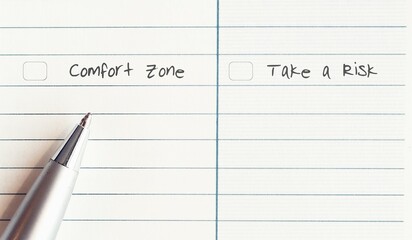 A silver pen on a line note paper with two choices to choose between COMFORT ZONE  and  TAKE A RISK - concept of making serious decision to step out from fear and start new thing