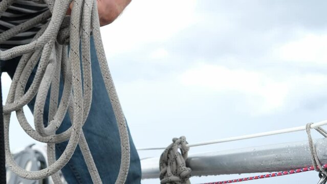 Close up of Yachtsman male hands holding rope on halyard winch of sailboat or on yacht