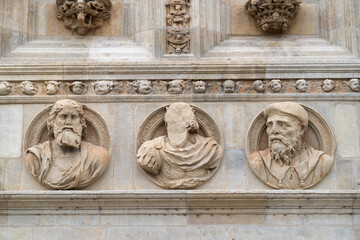 Antiguo bajo relieve en piedra con tres rostros de hombres antiguos, uno de ellos irreconocible.