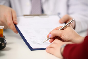 Doctor shows patient tablet with documents in clinic closeup. Signing and concluding medical...