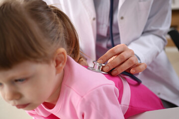 Little girl at doctor lung area examined with stethoscope. Cough bronchitis and asthma in children - obrazy, fototapety, plakaty