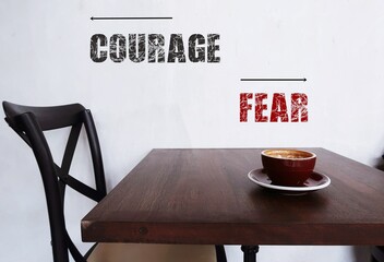 Wall with text inscription FEAR and COURAGE point to different direction, means to move from fear...