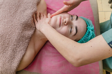 Facial massage. Facial skin care. Profile of a woman with the hands of a masseuse.