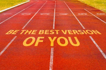 Kussenhoes Be The Best Version of You written on red running track in a stadium © graja