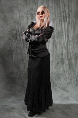 Stylish gothic blonde in a black dress with a corset and a white collar. Wearing round sunglasses