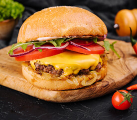 Tasty grilled home made burger with beef, tomato, cheese, onion and lettuce.