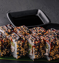 Sushi roll with fish, vegetables and cheese on black