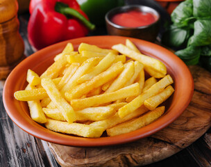 Fresh tasty french fries and red sauce on a wooden cutting board