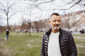 Smiling bestager man looking sideways in autumn park