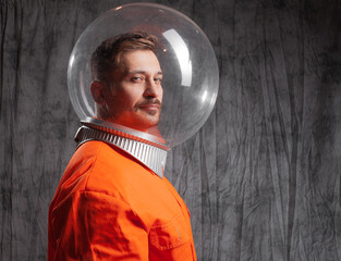 Retro futuristic astronaut in a spacesuit with a bright orange jumpsuit and a spherical glass helmet © Ulia Koltyrina