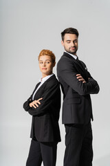 skeptical business people in black suits standing back to back with folded arms isolated on grey.