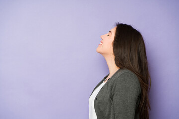 Fototapeta premium Relaxed young woman smiling looking up with her eyes closed
