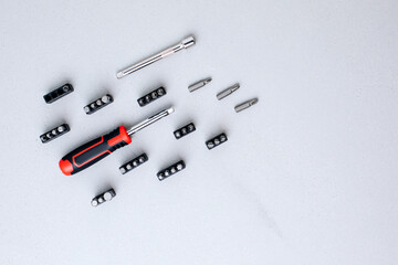 A set of working tools, screwdriver with bits for an answer on a gray concrete background. Flat lay