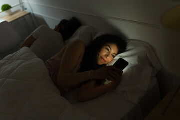 Obraz premium Excited woman texting before falling asleep